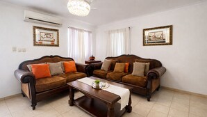 A living room with two brown leather sofas, a wooden coffee table, and a chandelier.
