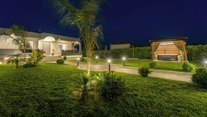 Een modern huis met een goed verlichte entree, een overdekt terras en een verzorgd gazon.