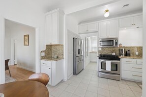 Eine Küche mit weißen Schränken, Granit Arbeitsplatten, Edelstahlgeräten und einem Essbereich mit einem Holztisch und Stühlen.