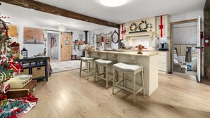 A kitchen with a wooden ceiling, a bar area with stools, and a Christmas tree.