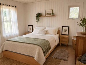 A bedroom with a bed, bedside tables, a window, and a wall-mounted shelf with a plant.