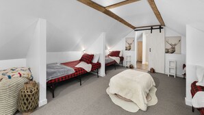 Un dormitorio tipo loft con dos camas, vigas de madera, paredes blancas y cuernos de ciervo en la pared.