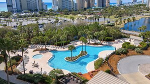 Ein Resort mit großem Pool, Palmen und Blick auf das Meer und die Skyline der Stadt.