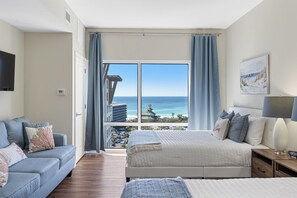 Ein Schlafzimmer mit Bett, einer Couch, einem Nachttisch und Meerblick.