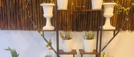 Una exhibición de plantas con varias macetas en estantes frente a un fondo de bambú.