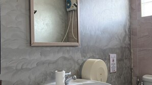 Un baño con lavamanos, espejo, dispensador de toallas y retrete.