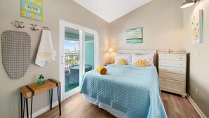 Un dormitorio con cama, cómoda, mesita de noche, toallero y vistas a la ciudad.