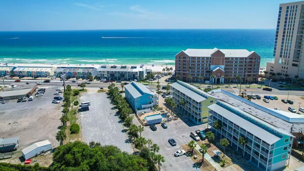 Un hotel frente al mar con varias edificaciones, un estacionamiento y vistas a la playa.