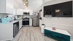 Una cocina moderna con armarios blancos, un refrigerador de acero inoxidable, un microondas y una estufa.