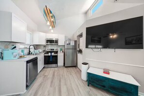 A modern kitchen with white cabinets, a stainless steel refrigerator, a microwave, and a stove. - West End, Beautiful Ocean Views, Across From Beach, Pool (Panama City Beach)