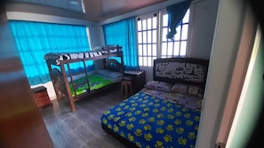 A room with bunk beds, a desk, and a bed with a patterned bedspread.