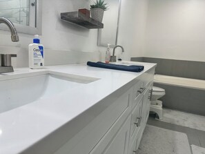 A bathroom with a white sink, a mirror, a shelf with a potted plant, and a toilet. - 2-bedroom townhome walking distance to NRG/FIFA World Cup w/ garage. (Houston)
