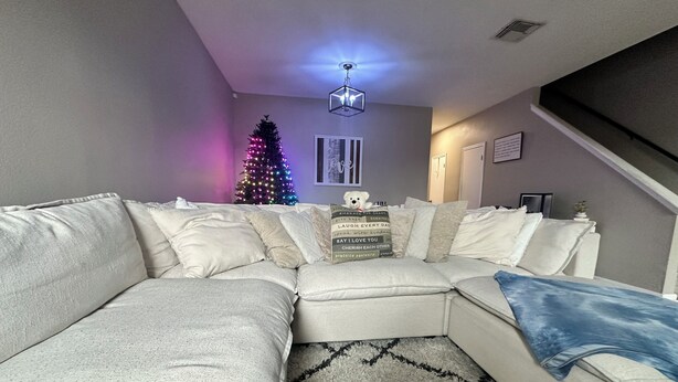 Una sala de estar moderna con un sofá modular, un tapete decorativo, un árbol de Navidad y una lámpara en el techo.