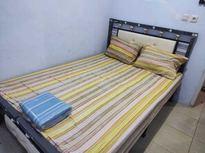 A bed with a striped bedspread, two pillows, and a blue blanket.