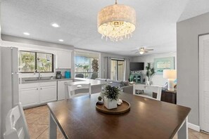 A modern kitchen with white cabinets, a dining table, and a chandelier. - 🦩Book Me Baby! Serenity at Silver Dunes🦩 (Destin)