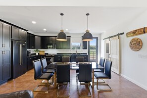 Une cuisine moderne avec des meubles de couleur sombre, un îlot central et des luminaires suspendus.