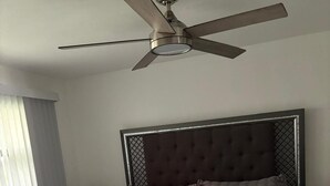 A bedroom with a bed, a ceiling fan, and a nightstand.