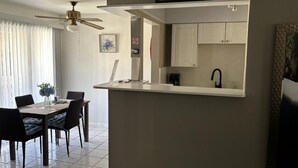 A modern kitchen with white cabinets, a black faucet, and a ceiling fan.