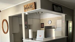 A compact kitchen with a built-in island, a clock, and a motivational sign.