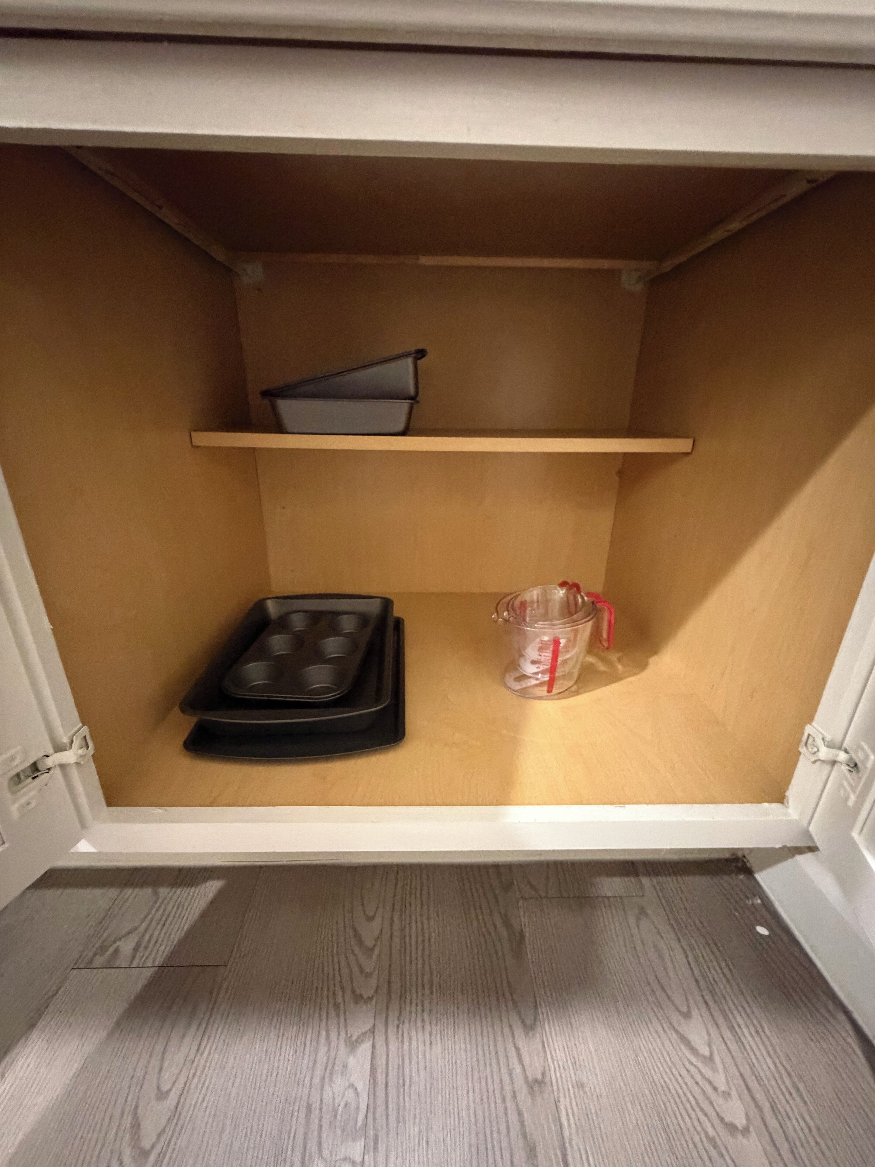 Un compartiment de rangement avec un plateau noir et un récipient en plastique transparent orné d’un ruban rouge.