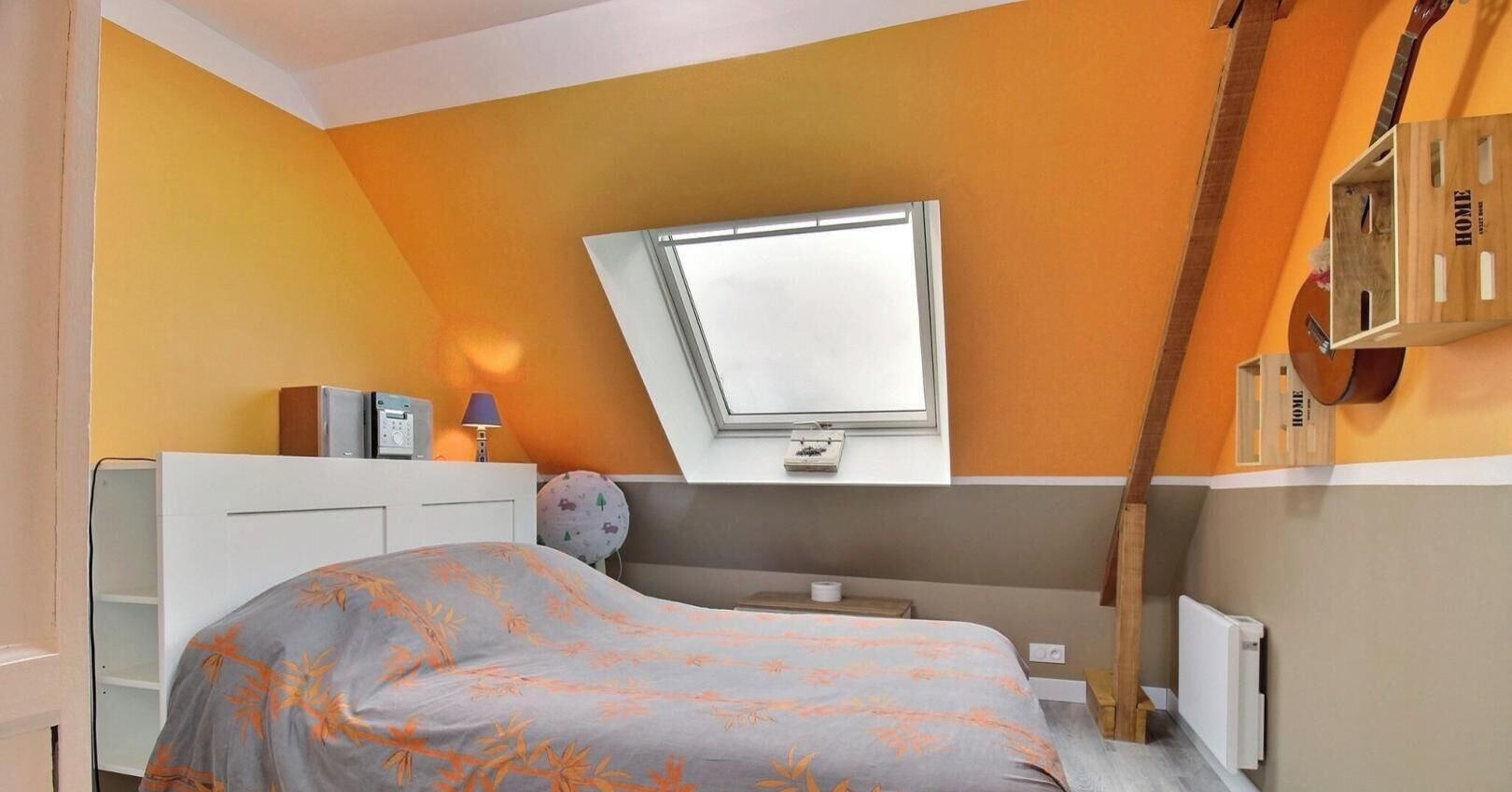 Ein Schlafzimmer mit Bett, Schreibtisch, Lampe, Fenster und Heizkörper.