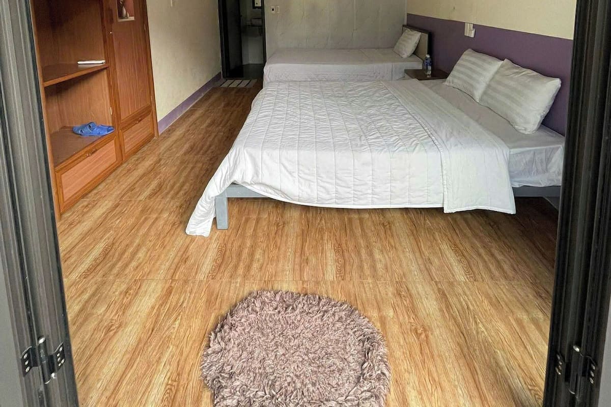 Une chambre à coucher avec un lit, une armoire en bois, un petit tapis et un ventilateur de plafond.