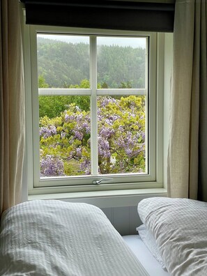 A room with a large window offering a view of a forested area and blooming trees.