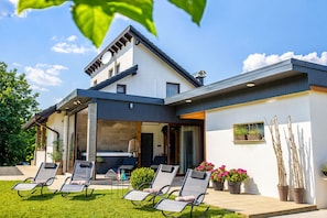 A modern two-story house with a patio, outdoor seating, and potted plants. - Modern home with jacuzzi, sauna, wellness and kids’ playground (Grabrovnik)