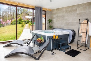 A modern bathroom with a hot tub, seating area, and a view of the garden. - Modern home with jacuzzi, sauna, wellness and kids’ playground (Grabrovnik)