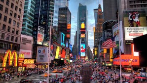 Una calle urbana concurrida, con edificios altos, carteles publicitarios y una multitud de personas.