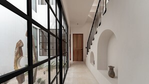 Un couloir avec une cloison en verre, une porte en bois et un vase accroché au mur.