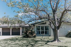 Ein Wohnhaus mit Garage, einem großen Baum im Vorgarten und einem gepflegten Rasen.