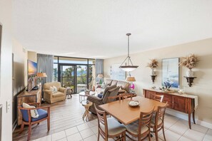 A spacious living area with a dining table, sofas, and a TV. - Second floor oceanfront custom condo with spa like baths (Myrtle Beach)