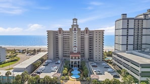 A multi-story hotel with a central tower, a parking lot, and a view of the beach. - Second floor oceanfront custom condo with spa like baths (Myrtle Beach)