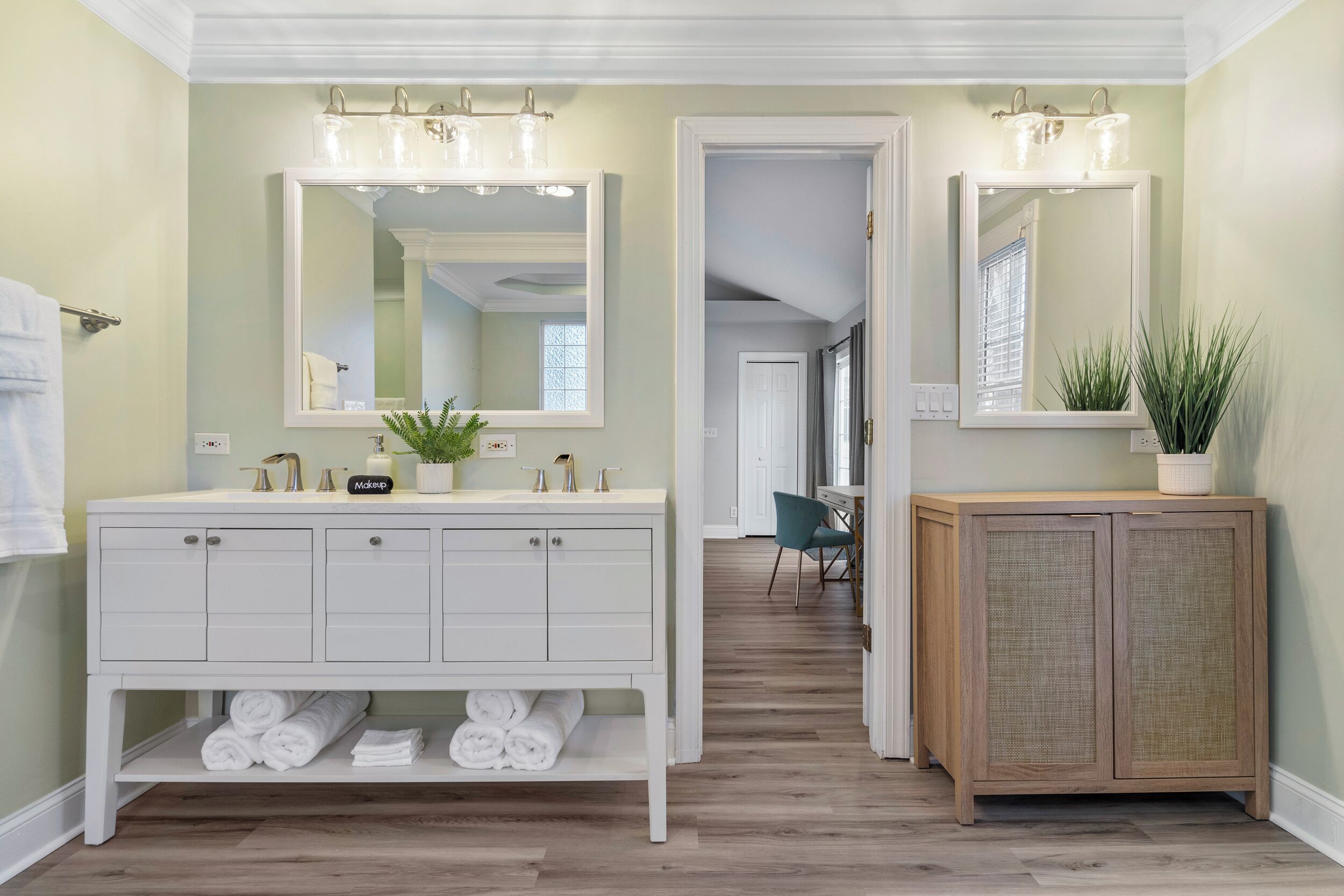 A bathroom with a white vanity, a mirror, and a wooden cabinet.