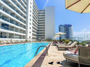A hotel pool area with lounge chairs, umbrellas, and a clear blue pool. - Oceanfront Suite with Coworking & Pool (Cartagena de Indias)