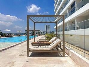 A rooftop pool area with lounge chairs, a pergola, and a view of the city skyline. - Oceanfront Suite with Coworking & Pool (Cartagena de Indias)