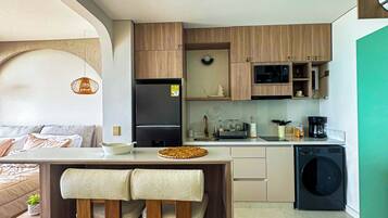 A modern kitchen with wooden cabinets, a built-in microwave, and a washing machine.
