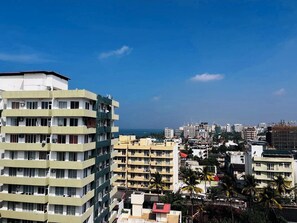 Un edificio a più piani con balconi, vista sul mare e altri edifici residenziali sullo sfondo.