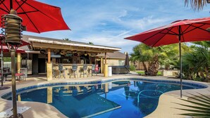 A pool area with a bar, chairs, and umbrellas. - Modern upgraded 3-bedroom home in sunny Scottsdale! (Scottsdale)