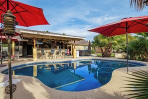 A pool area with a bar, chairs, and umbrellas. - Modern upgraded 3-bedroom home in sunny Scottsdale! (Scottsdale)