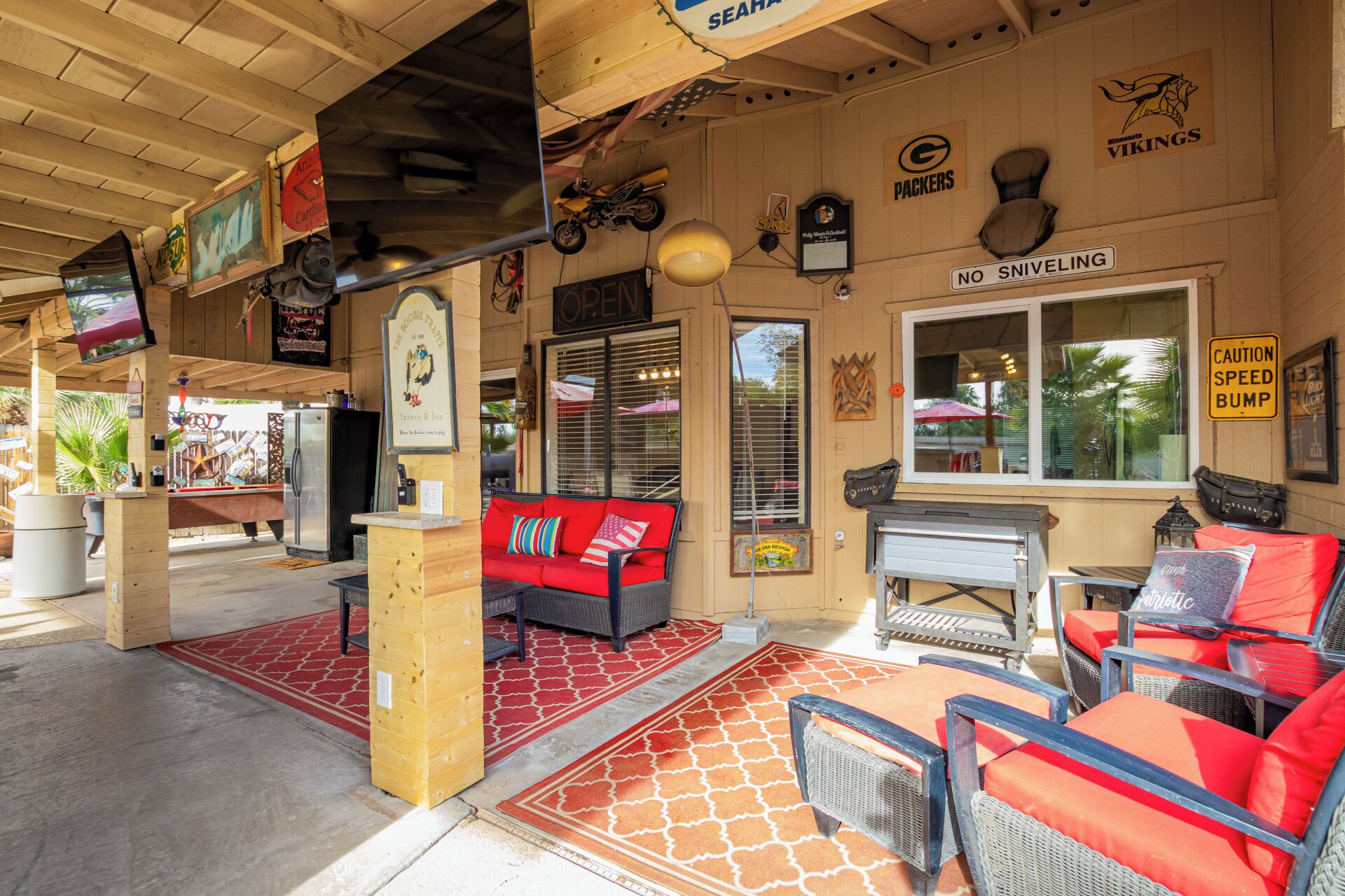 Un espacio de estar al aire libre cubierto con muebles de mimbre, un sofá rojo y un letrero que prohíbe los sollozos.