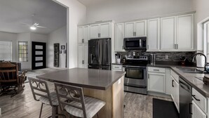 A modern kitchen with white cabinetry, stainless steel appliances, and a central island with seating. - Modern upgraded 3-bedroom home in sunny Scottsdale! (Scottsdale)