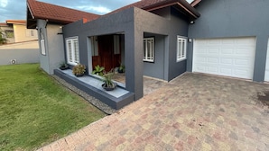 A modern house with a grey exterior, a red-tiled roof, and a paved driveway. - Private Kingston 6 Villa w/ Pool, Swim-Up Bar & Outdoor Kitchen Near Liguanea (Kingston)