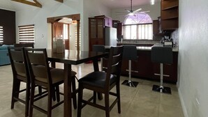 A spacious dining area with a high ceiling, wooden beams, and pendant lighting. - Private Kingston 6 Villa w/ Pool, Swim-Up Bar & Outdoor Kitchen Near Liguanea (Kingston)