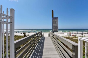 A wooden boardwalk leading to a beach with a signboard. - Beachfront Bliss: 3-bedroom, 2-bath condo in Panama City Beach, sleeps 7. (Panama City Beach)