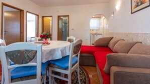 A compact living space with a dining area, a sofa, and a kitchen area. - Holiday apartment with terrace and barbecue (Malinska)