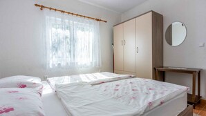 A bedroom with a bed, a wardrobe, a mirror, and a small table. - Holiday apartment with terrace and barbecue (Malinska)