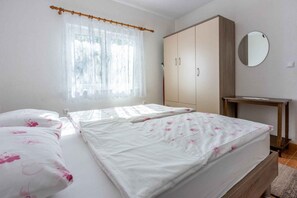 A bedroom with a bed, a wardrobe, a mirror, and a small table. - Holiday apartment with terrace and barbecue (Malinska)