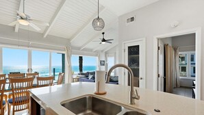 A kitchen with a large island, double sink, and a view of the ocean. - Oceanfront Condo | Balcony, Fire Pit | Shared Beach | Sleeps 6 (Oceanside)